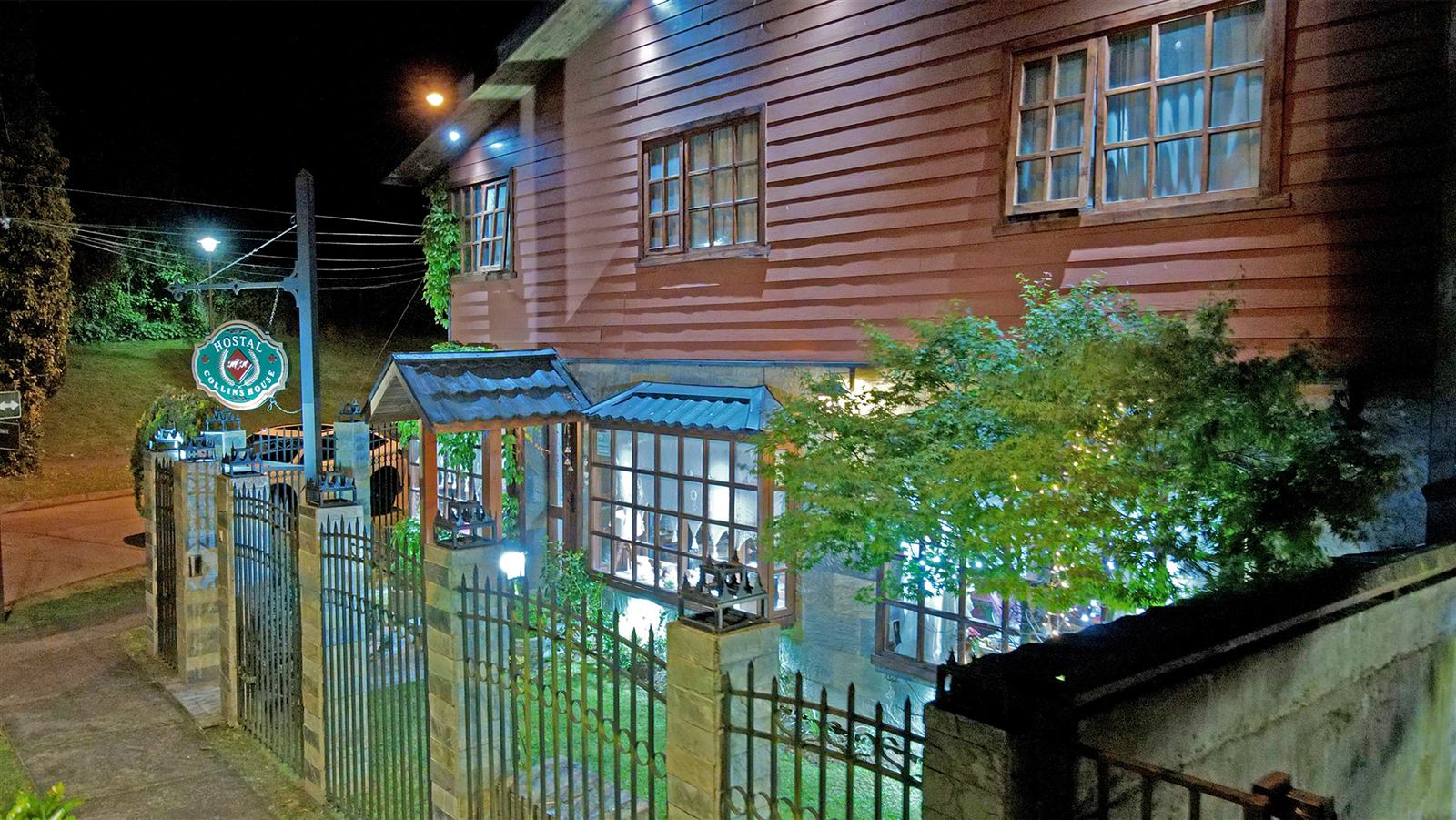 Entrada del hostal iluminada al anochecer, con el letrero colgante