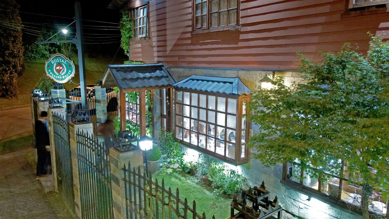 Fachada del hostal iluminada de noche, vista desde el jardín