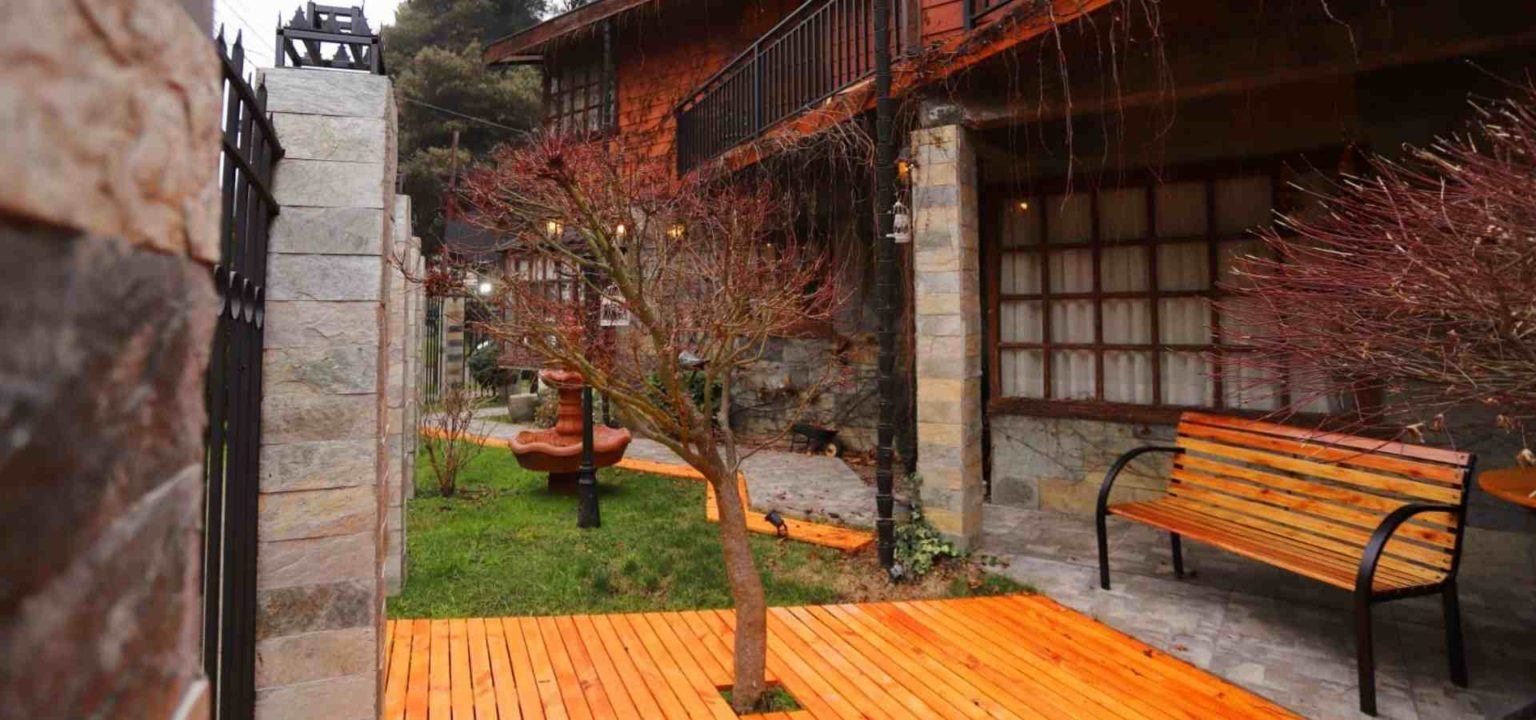 Terraza de madera con banca y jardín interior del hostal